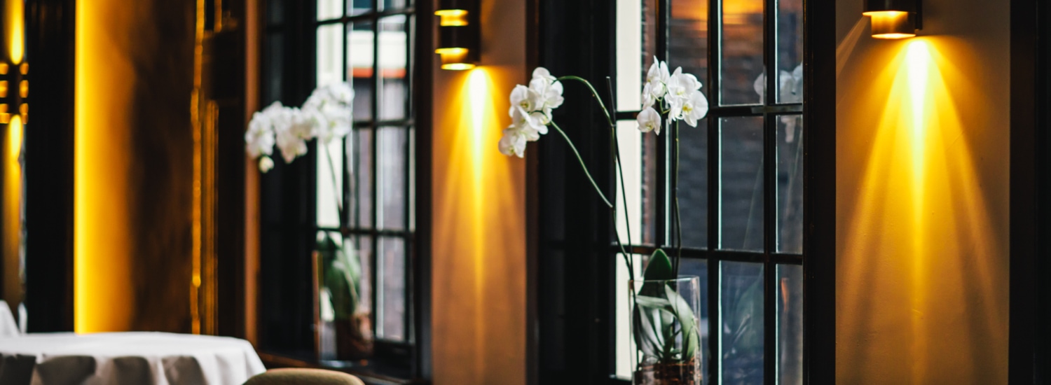 An impression of 2 Michelin Star Restaurant Vinkeles in luxury boutique hotel The Dylan Amsterdam. Orchids in the windows and the light are lit, which gives a warm feeling in the restaurant.