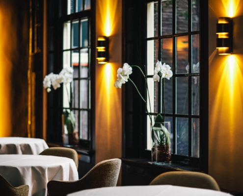 An impression of 2 Michelin Star Restaurant Vinkeles in luxury boutique hotel The Dylan Amsterdam. Orchids in the windows and the light are lit, which gives a warm feeling in the restaurant.
