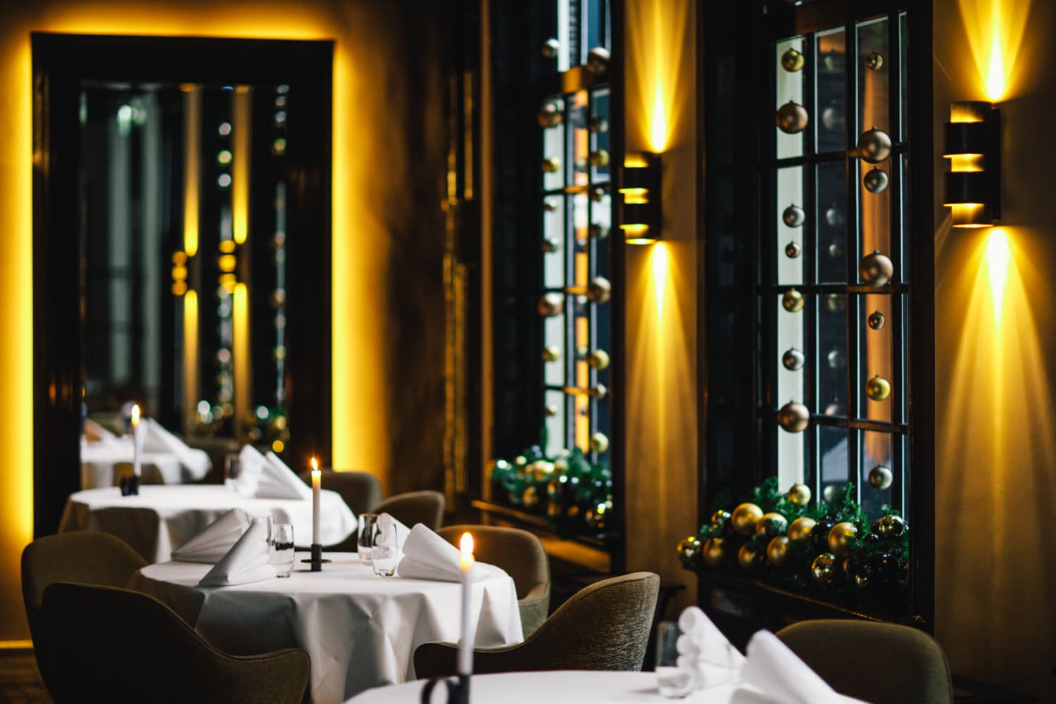 A set table during Christmas in 2 Michelin Star Restaurant Vinkeles, in luxury boutique hotel The Dylan Amsterdam. The serviettes are folded, glasses are polished and the candles are lit.