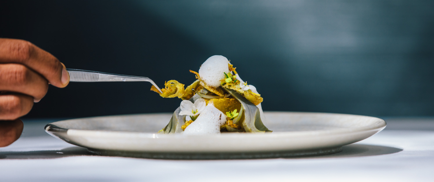 Executive Chef Jurgen van der Zalm finishing an artichoke dish at 2* Michelin Restaurant Vinkeles. This vegetarian dish is finished by adding a final touch with a pincet, placing this on top of the foam.