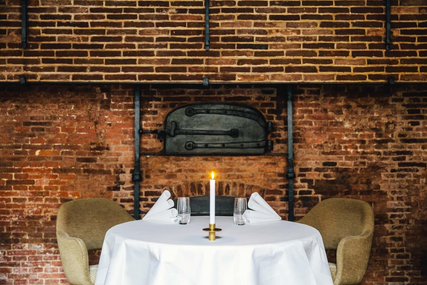A set table in 2 Michelin Star Restaurant Vinkeles, in luxury boutique hotel The Dylan Amsterdam. The serviettes are folded, glasses are polished and the candles are lit.